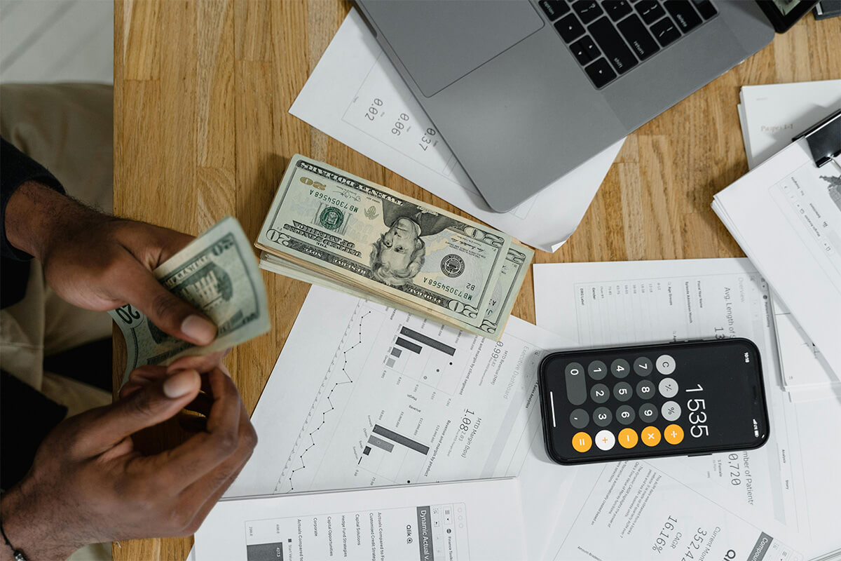 A man counting money next to a calculator